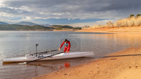 Senior Ruderer in der Takelage seiner Rudermuschel am Ufer des Carter Lake im Norden Colorados in winterlicher Landschaft