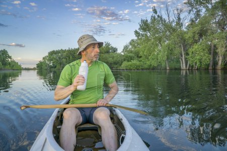 Photo for Senior male paddler in a decked expedition canoe on a calm lake in northern Colorado - Royalty Free Image