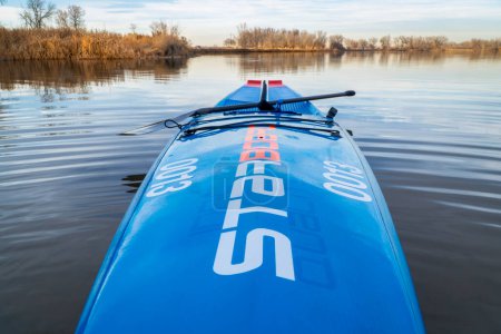 Photo for Fort Collins, CO, USA - November 19, 2019: Racing stand up paddleboard, All Star by Starboard, on a shore of a calm lake in late fall scenery, paddling workout and fitness concept. - Royalty Free Image