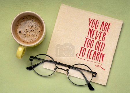 Usted nunca es demasiado viejo también aprender - palabras motivacionales en una servilleta con café y vasos de lectura - concepto de educación continua