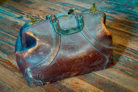 Téléchargez les photos : Vieux sac de médecine en cuir vintage sur un sol en bois poussiéreux - en image libre de droit