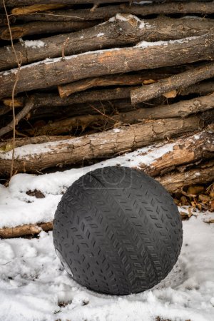 heavy, 50 lb, slam ball filled with sand in a snowy backyard, exercise and functional fitness concept