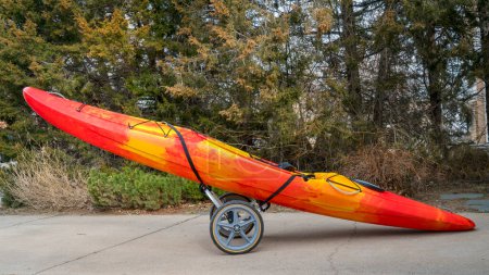 colorful river kayak on a folding cart in a driveway - river running shuttle concept