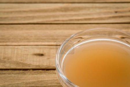 Photo for Unfiltered, raw apple cider vinegar with mother - a small glass bowl on wooden table - Royalty Free Image