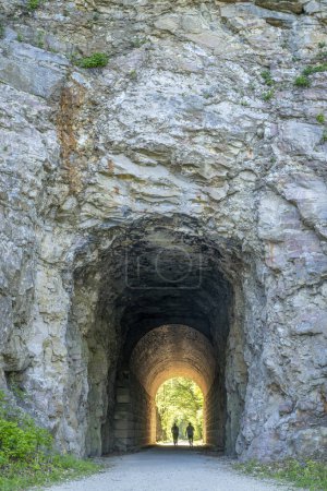 Téléchargez les photos : Silhouette d'un couple marchant dans un tunnel sur Katy Trail près de Rocheport, Missouri. Le sentier Katy est un sentier cyclable de 237 milles converti d'un ancien chemin de fer. - en image libre de droit