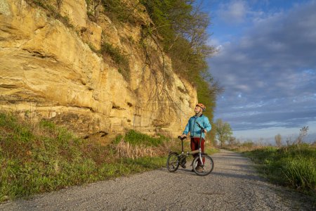 Photo for Senior male cyclist riding a folding bike on Steamboat Trace, bike trail converted from an abandoned railroad, near Peru, Nebraska, springtime morning scenery - Royalty Free Image