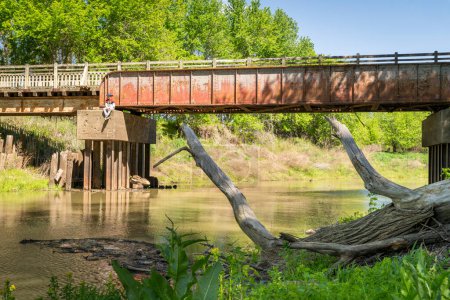 Foto de Easley, MO, Estados Unidos - 21 de abril de 2024: Katy Trail bridge over Bonne Femme Creak with a lonely man sitting on a pillar, spring scenery. - Imagen libre de derechos