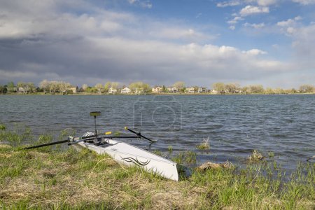 Foto de Loveland, CO, Estados Unidos - 2 de mayo de 2024: Cáscara de remo en Liteboat en una costa cubierta de hierba, Boyd Lake State Park en paisajes de primavera. - Imagen libre de derechos