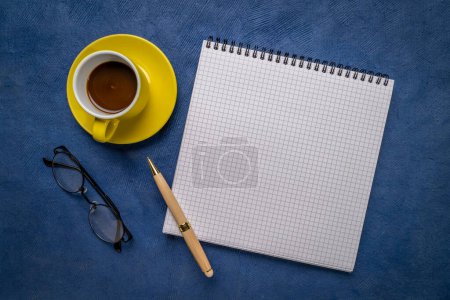Photo for Blank spiral notebook with ruled paper, flat lay with coffee, reading glasses and pen on blue textured art paper - Royalty Free Image