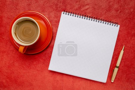 Foto de Cuaderno en espiral en blanco con papel regulado, plano con café sobre papel de arte con textura roja - Imagen libre de derechos