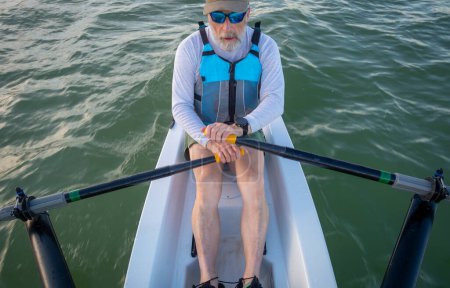 senior man in a rowing shell on a lake in Colorado