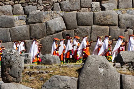 Foto de Mujeres llevando comida con traje tradicional Festival Inti Raymi Cusco Perú Sudamérica con muro de piedra Inca - Imagen libre de derechos