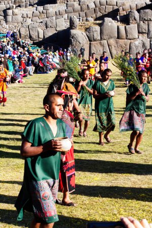 Téléchargez les photos : Festival Inti Raymi Cusco Pérou Hommes en costume traditionnel entrant avec des spectateurs et des murs de pierre inca en arrière-plan - en image libre de droit