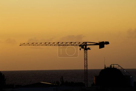 Sihouette Of Crane Over Buildings With Yellow Cloudy Sky And Ocean In Background Papeete French Polynesia Tahiti South Pacific