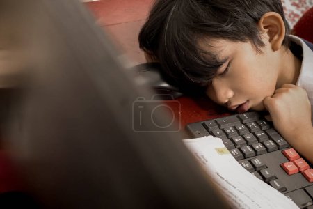 Photo for Asian boy fallen asleep in front of his computer during online school from home - Royalty Free Image