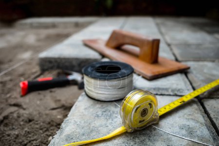 Photo for Closeup view of tools, utensils and materials used for paving block floor construction work - Royalty Free Image