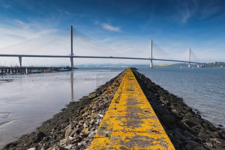 Queensferry Crossing South road bridge across Firth of Forth river estuary in Scotland, UK. Leading line composition with breakwater.