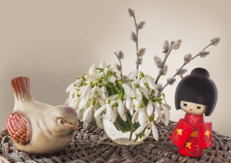 Concept of Japanese holiday of contemplating snowdrops and waiting for spring. Traditional Japanese Kokeshi doll (mass production), bird figurine (mass production) and snowdrops with willow branches.