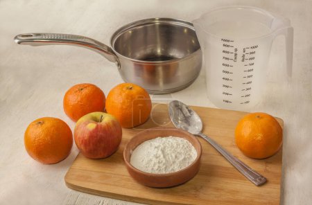Almidón, naranjas, manzana y una cacerola para hacer jalea 