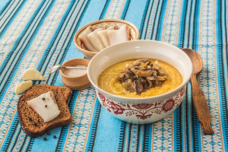 Téléchargez les photos : Porridge de maïs - banosh (ou banush) avec bacon grillé, oignons, pain de seigle avec poivre et bacon, ail et champignons. La vaisselle est considérée comme faisant partie de la cuisine ukrainienne, en particulier Hutsul - en image libre de droit