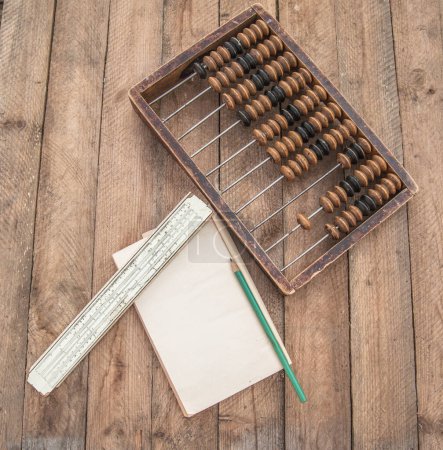 Old abacus, the paper with a pencil and sliding rule on a wooden table. Flat lay