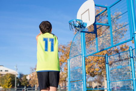 Foto de Bajo ángulo de un niño jugando baloncesto en una cancha de baloncesto urbana listo para disparar una canasta. horizontal - Imagen libre de derechos