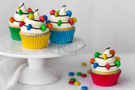 Téléchargez les photos : Cakestand avec des cupcakes de Noël décorés avec des cordes de bonbons colorés lumières de Noël - en image libre de droit
