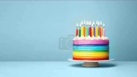 Foto de Pastel colorido del cumpleaños del arco iris con velas coloridas del cumpleaños del arco iris para una fiesta, fondo azul con espacio de la copia - Imagen libre de derechos