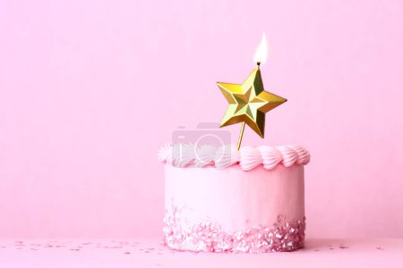 Photo for Pink frosted birthday cake with one gold star birthday candle and heart shaped sprinkles against a plain pink background - Royalty Free Image