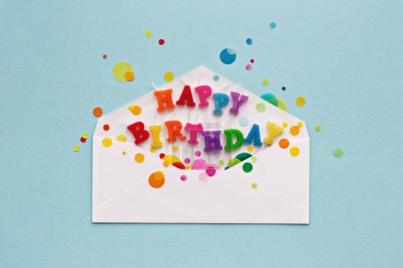Photo for Birthday card envelope with colorful happy birthday candles and rainbow colored celebration confetti, overhead view - Royalty Free Image