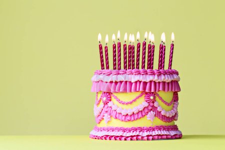 Téléchargez les photos : Gâteau d'anniversaire vintage rose et jaune avec bougies d'anniversaire et volants et volants passepoilus sur fond jaune - en image libre de droit