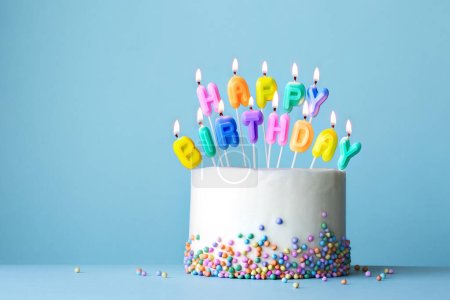 Foto de Colorido pastel de cumpleaños con velas de cumpleaños ortografía feliz cumpleaños contra un fondo azul - Imagen libre de derechos
