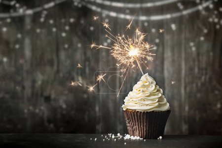Téléchargez les photos : Cupcake de célébration d'anniversaire avec scintillant sur un fond en bois - en image libre de droit