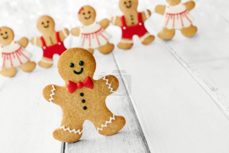 Photo for Gingerbread man with bow tie and buttons, row of gingerbread men behind and copy space to side - Royalty Free Image