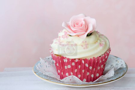 Foto de Cupcake decorado con una rosa de azúcar se levantó sobre un fondo rosa - Imagen libre de derechos
