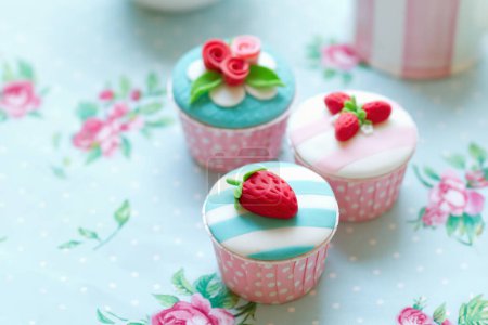 Foto de Magdalenas decoradas con fresas fondantes y rosas en copas de cupcakes de lunares rosados - Imagen libre de derechos