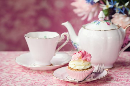 Foto de Té de la tarde servido con un cupcake de flores en porcelana vintage - Imagen libre de derechos