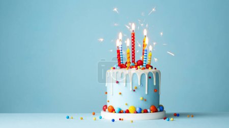 Colorful celebration birthday cake with colorful birthday candles and sparklers against a blue background