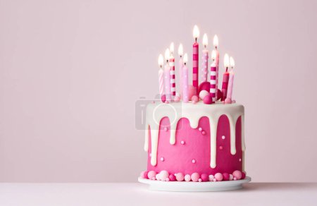 Foto de Pastel de cumpleaños de celebración rosa con glaseado por goteo y velas de cumpleaños rosas - Imagen libre de derechos