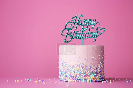 Photo for Celebration birthday cake with happy birthday cake pick against a pink background - Royalty Free Image