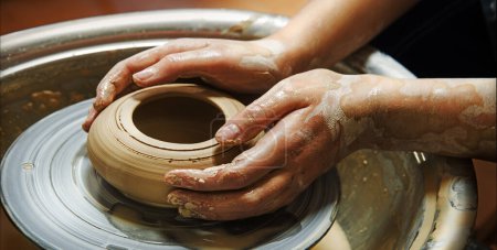 Photo for Closeup rural bible god male artisan worker dirty arm touch tool teach ancient retro old earthen culture water mug pitcher vessel ware. Rustic antique wet hobby table girl learn make pan dish design - Royalty Free Image