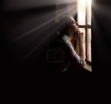 Photo for Adult lone worry fail poor holy devot jew lady hand ask beg plead Jesus Christ old Ukraine war history. Cold young teen age human face think wait life love dark hut home room text space look light sky - Royalty Free Image
