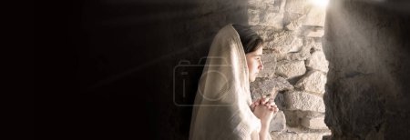 Photo for Lone sad worry Jewish human child kid face think ask holy Lord light faith hope love. Young lady stand wait good news empty dark black burial house home room wall feel fear pain grief war text space - Royalty Free Image