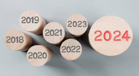 Photo for Photo of round wooden block rows with gray numbers of passed years and one of them standing out with red number 2024 imprinted on wooden surface. New Year concept. - Royalty Free Image