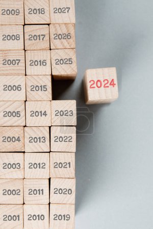 Photo for Photo of wooden block rows with gray numbers of passed years and one of them standing out with red number 2024 imprinted on wooden surface. New Year concept. - Royalty Free Image