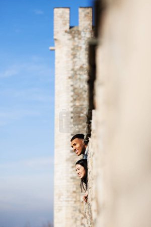Photo for Multiracial couple enjoying the view from the walls of an old fortress. Man and woman in love. - Royalty Free Image