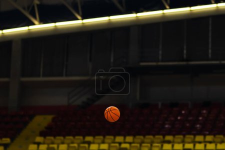 Téléchargez les photos : Basket ball in the air against dark hall background - en image libre de droit