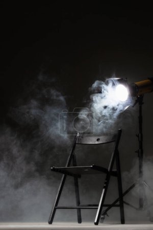 Photo for Movie directors chair on set with light on a stand. Smoke in the background. - Royalty Free Image