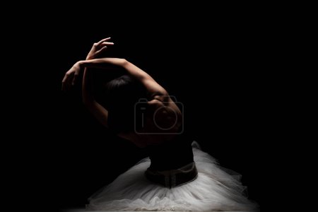 Photo for Half silhouette modern ballet dancer. Balerina posing on dark background - Royalty Free Image