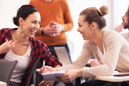 Foto de Estudiantes escuchando a un profesor en un aula. Chicas jóvenes inteligentes hablando sonriendo y dando consejos el uno al otro. - Imagen libre de derechos